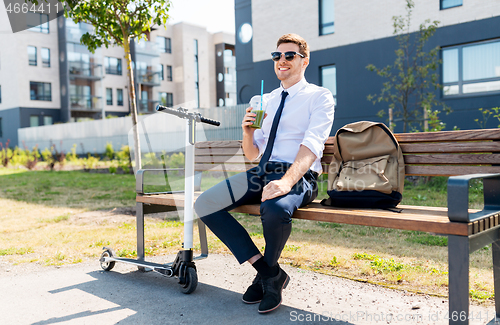 Image of businessman with scooter drinking smoothie in city
