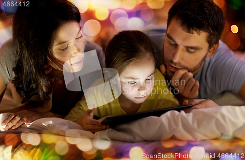 Image of family with tablet pc in bed at night at home