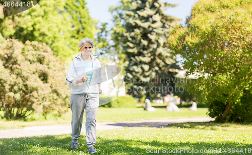 Image of senior woman running along summer park