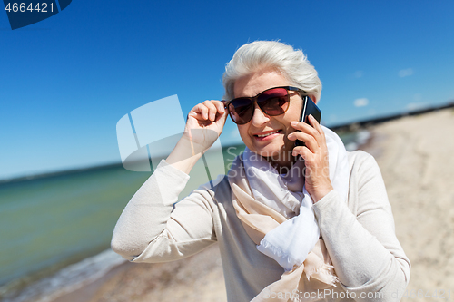 Image of senior woman calling on smartphone on beach