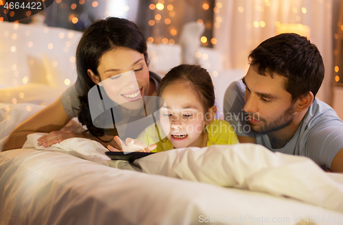 Image of family with tablet pc in bed at night at home