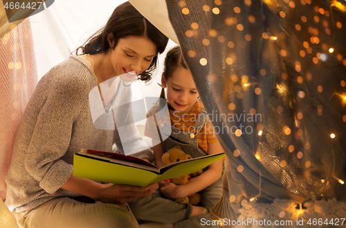 Image of happy family reading book in kids tent at home