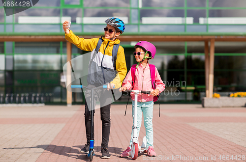 Image of happy school kids with scooters taking selfie