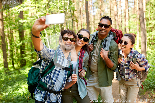 Image of friends with backpacks hiking and taking selfie