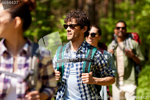 Image of group of friends with backpacks hiking in forest