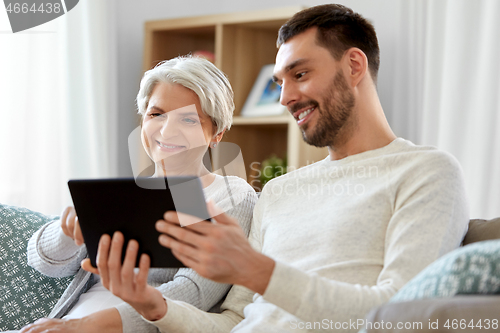 Image of old mother and adult son with tablet pc at home