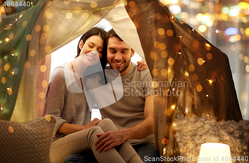 Image of happy couple in kids tent at home