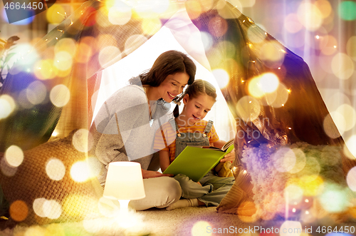 Image of happy family reading book in kids tent at home