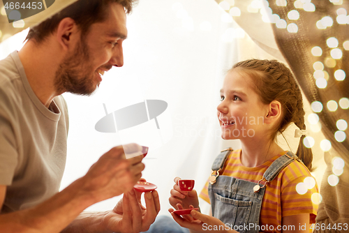 Image of family playing tea party in kids tent at home