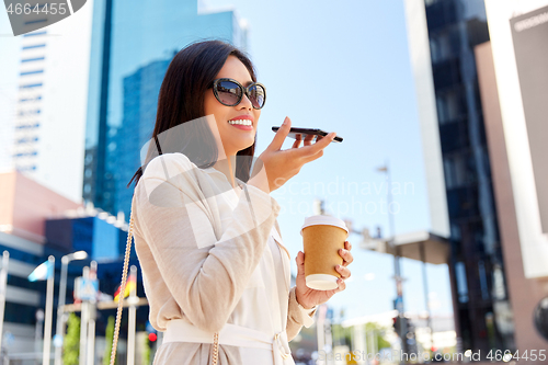 Image of woman recording voice by smartphone in city