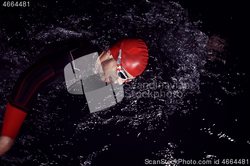 Image of triathlon athlete swimming in dark night wearing wetsuit