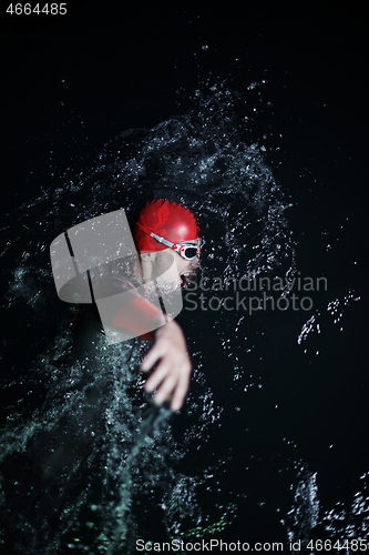 Image of real triathlon athlete swimming in dark night