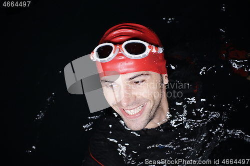 Image of authentic triathlete swimmer having a break during hard training on night