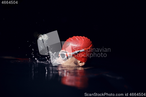 Image of authentic triathlete swimmer having a break during hard training on night