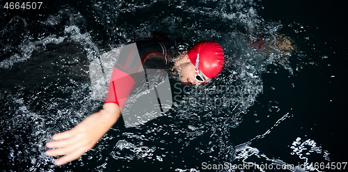 Image of triathlon athlete swimming in dark night wearing wetsuit