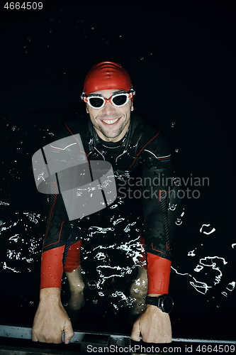 Image of authentic triathlete swimmer having a break during hard training on night