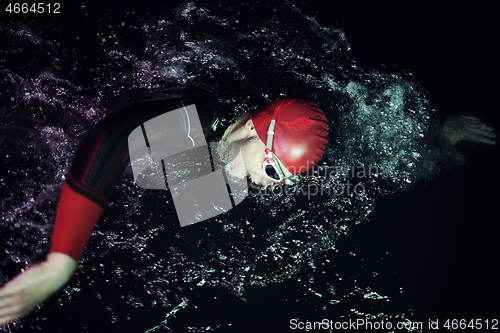 Image of real triathlon athlete swimming in dark night