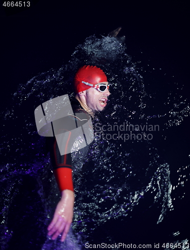 Image of real triathlon athlete swimming in dark night