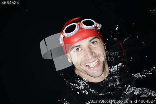 Image of authentic triathlete swimmer having a break during hard training on night