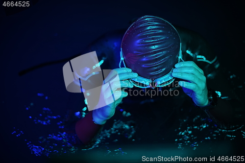 Image of authentic triathlete swimmer having a break during hard training on night neon gel light