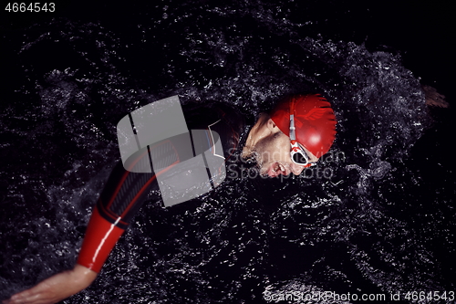 Image of triathlon athlete swimming in dark night wearing wetsuit