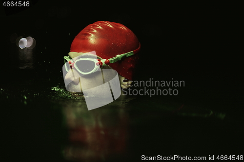 Image of authentic triathlete swimmer having a break during hard training on night neon gel light