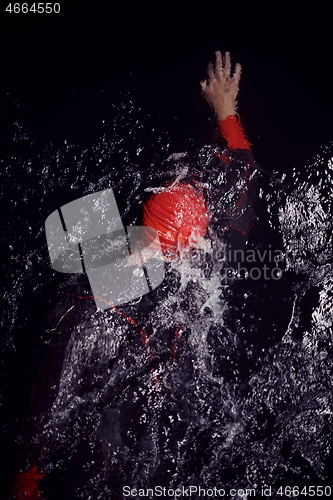 Image of triathlon athlete swimming in dark night wearing wetsuit