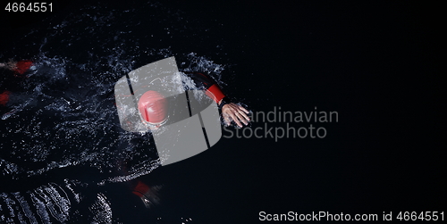 Image of triathlon athlete swimming in dark night wearing wetsuit