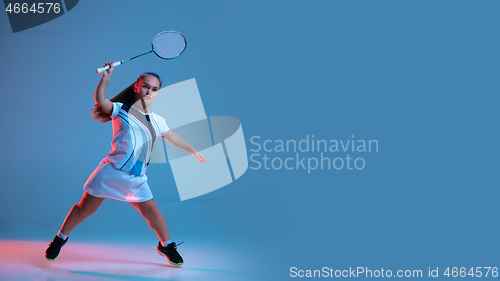 Image of Beautiful dwarf woman practicing in badminton isolated on blue background in neon light