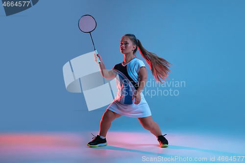 Image of Beautiful dwarf woman practicing in badminton isolated on blue background in neon light