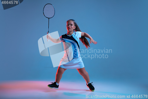 Image of Beautiful dwarf woman practicing in badminton isolated on blue background in neon light