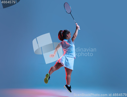 Image of Beautiful dwarf woman practicing in badminton isolated on blue background in neon light