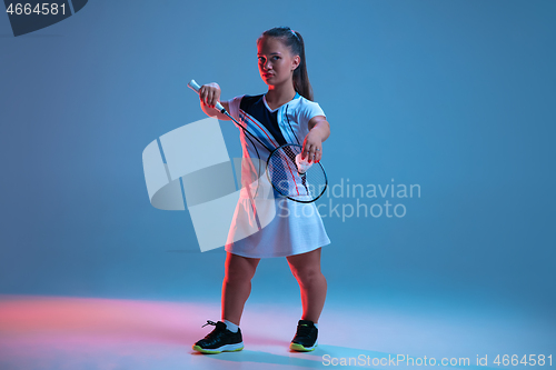 Image of Beautiful dwarf woman practicing in badminton isolated on blue background in neon light