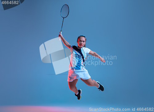 Image of Beautiful dwarf woman practicing in badminton isolated on blue background in neon light