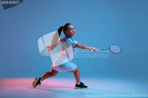 Image of Beautiful dwarf woman practicing in badminton isolated on blue background in neon light