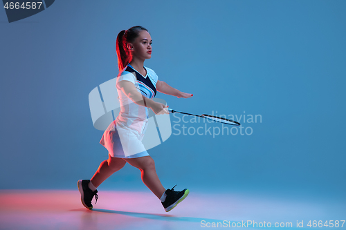 Image of Beautiful dwarf woman practicing in badminton isolated on blue background in neon light