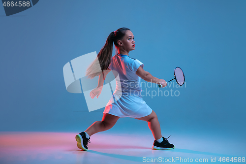 Image of Beautiful dwarf woman practicing in badminton isolated on blue background in neon light