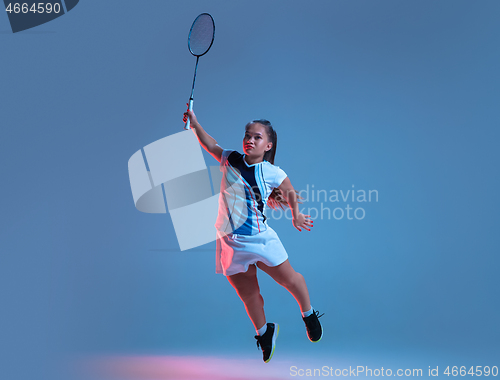 Image of Beautiful dwarf woman practicing in badminton isolated on blue background in neon light