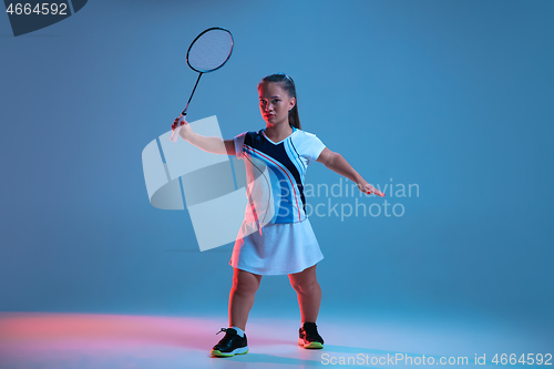 Image of Beautiful dwarf woman practicing in badminton isolated on blue background in neon light