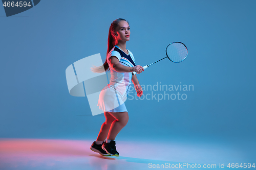 Image of Beautiful dwarf woman practicing in badminton isolated on blue background in neon light