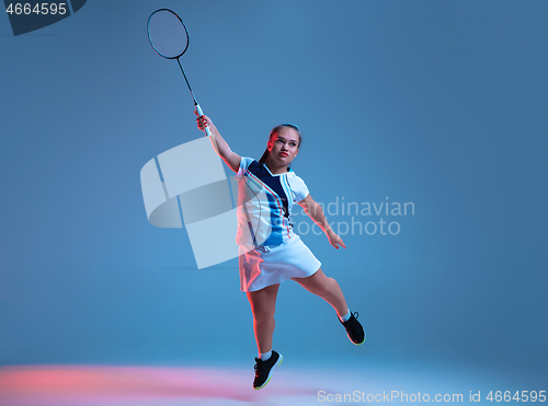 Image of Beautiful dwarf woman practicing in badminton isolated on blue background in neon light