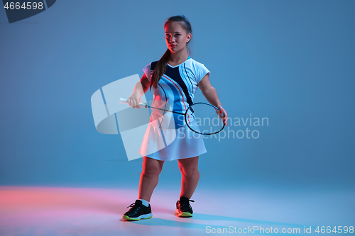 Image of Beautiful dwarf woman practicing in badminton isolated on blue background in neon light