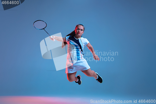 Image of Beautiful dwarf woman practicing in badminton isolated on blue background in neon light