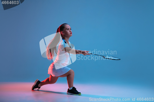 Image of Beautiful dwarf woman practicing in badminton isolated on blue background in neon light