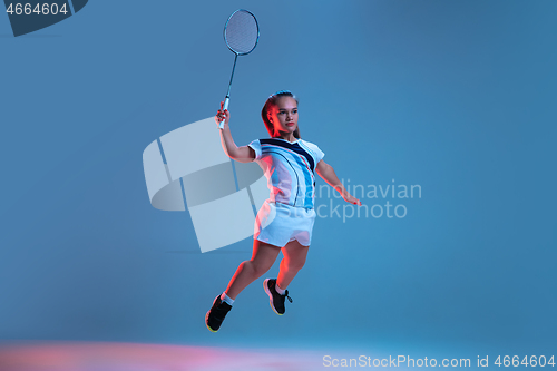 Image of Beautiful dwarf woman practicing in badminton isolated on blue background in neon light