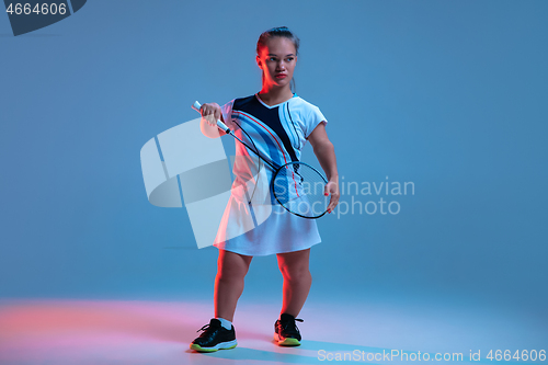 Image of Beautiful dwarf woman practicing in badminton isolated on blue background in neon light