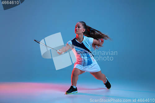 Image of Beautiful dwarf woman practicing in badminton isolated on blue background in neon light