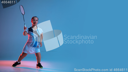 Image of Beautiful dwarf woman practicing in badminton isolated on blue background in neon light