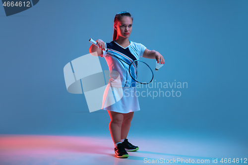 Image of Beautiful dwarf woman practicing in badminton isolated on blue background in neon light