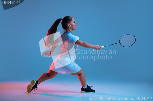 Image of Beautiful dwarf woman practicing in badminton isolated on blue background in neon light